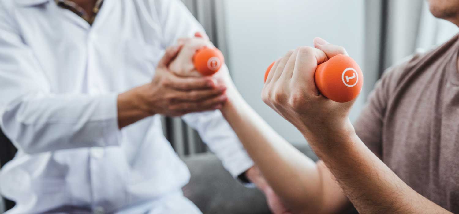 Patient holding orange one-pound hand weights doing physical therapy with a provider.