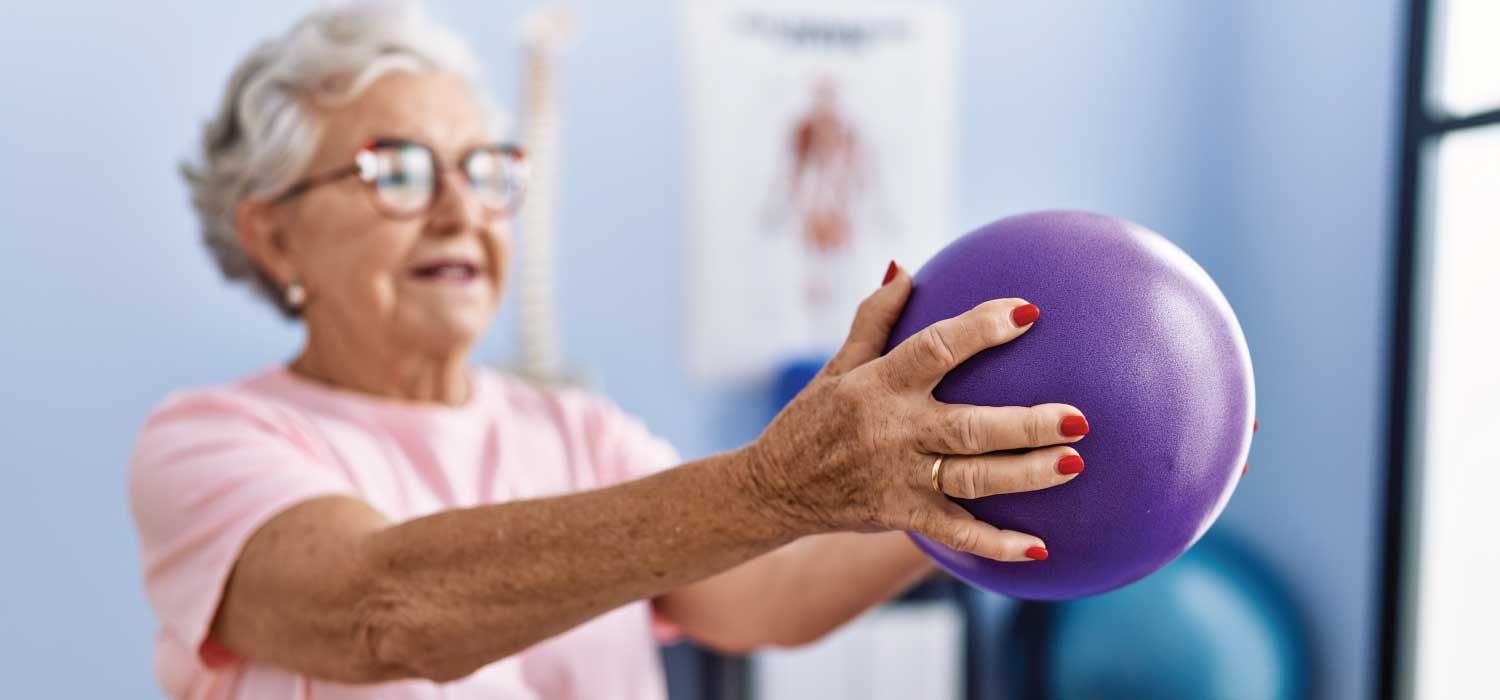 Chiropractic-Care Senior lady holding a purple ball doing physical therapy
