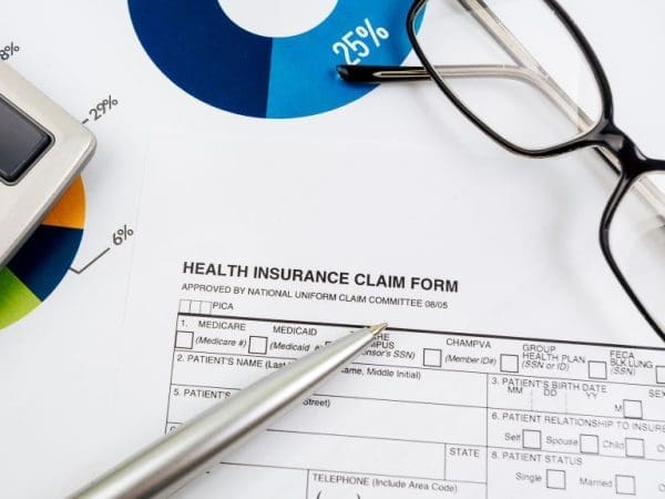 Health Insurance Claim form with a pen, glasses and billing detail spaces.