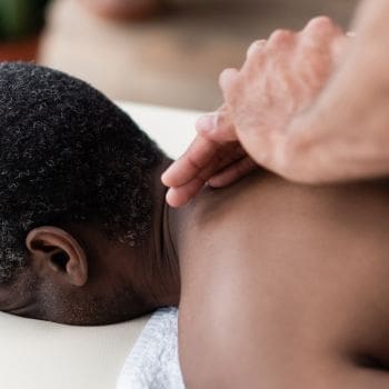 A male's upper back getting a massage.