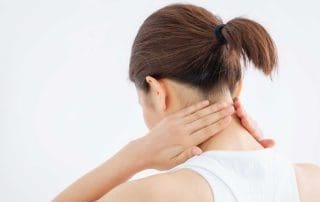 A woman touches her neck with both hands as if touches sore muscles or an accident injury.