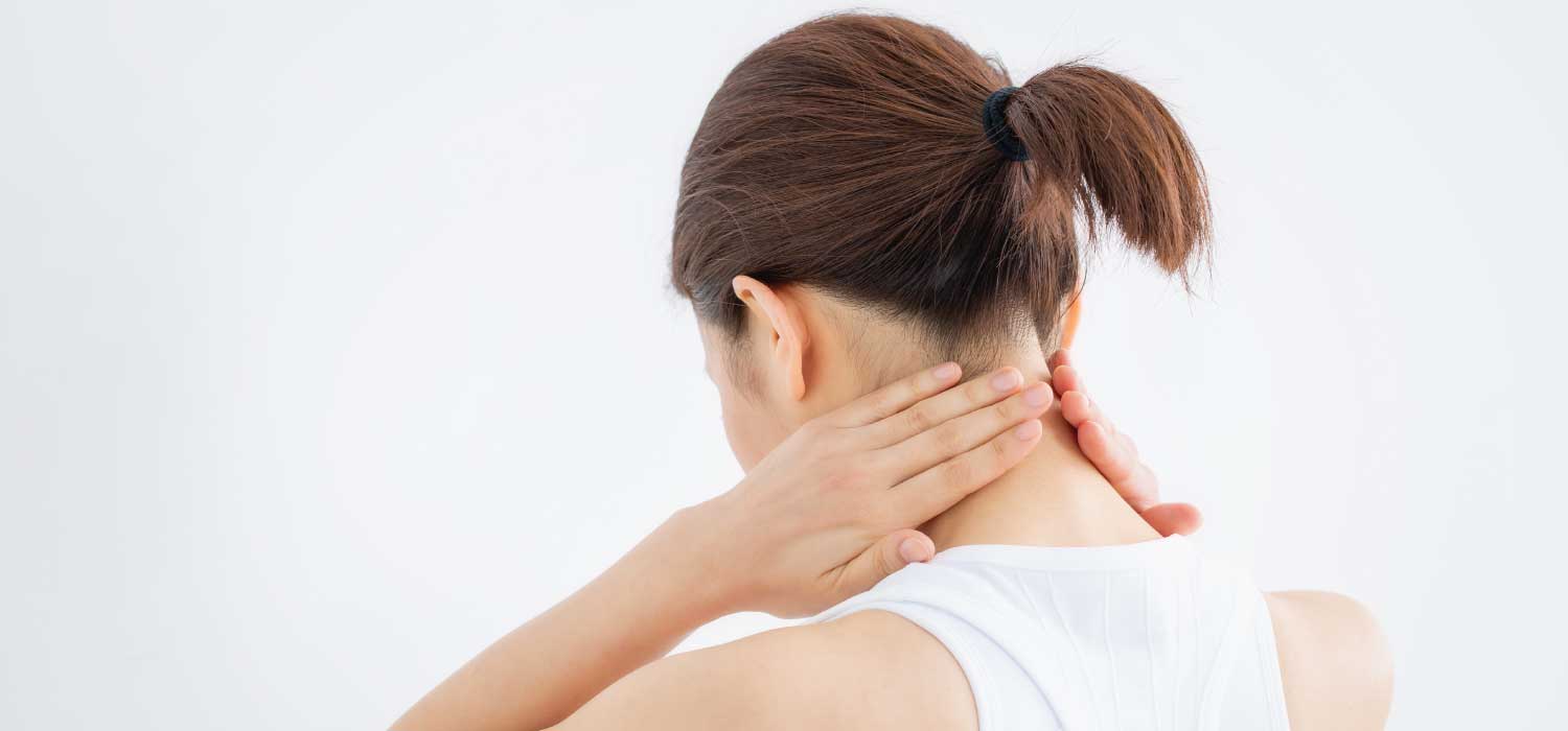 A woman touches her neck with both hands as if touches sore muscles or an accident injury.